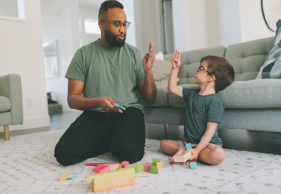 photo of a dark skinned man with a beard and glasses Signing with a light skinned child with short hair and glasses